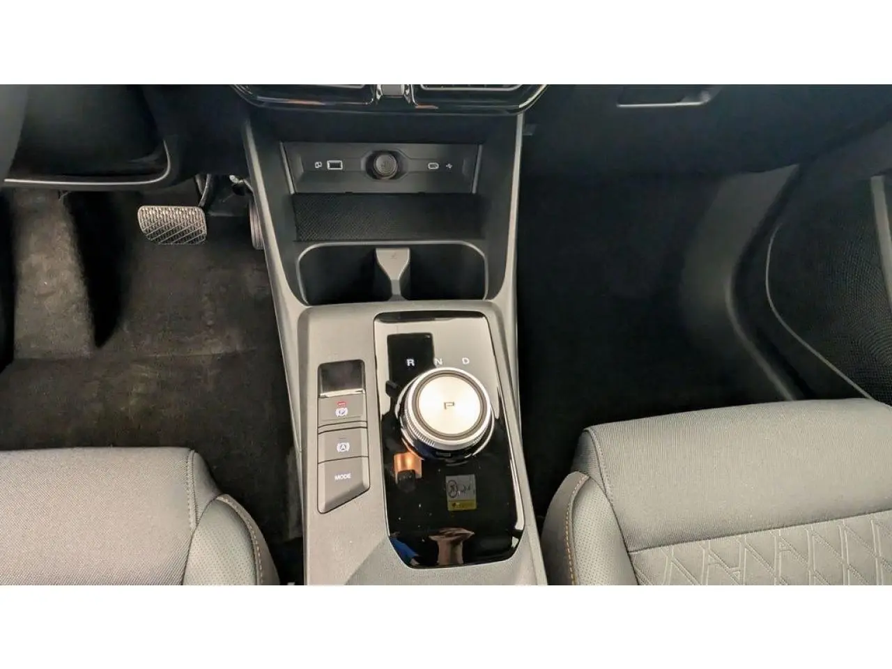 Vue intérieure centrée sur la console centrale avec molette de boîte auto et sièges tissu/similicuir gris clair.