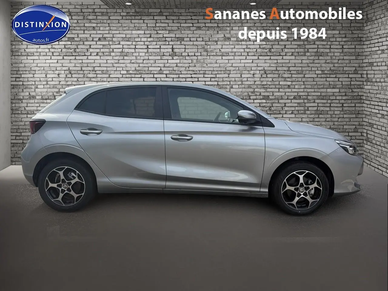 Vue latérale droite du MG3 1.5 Hybrid+ 195 Luxury en Cosmic Silver avec jantes distinctives, sur fond de mur en briques.