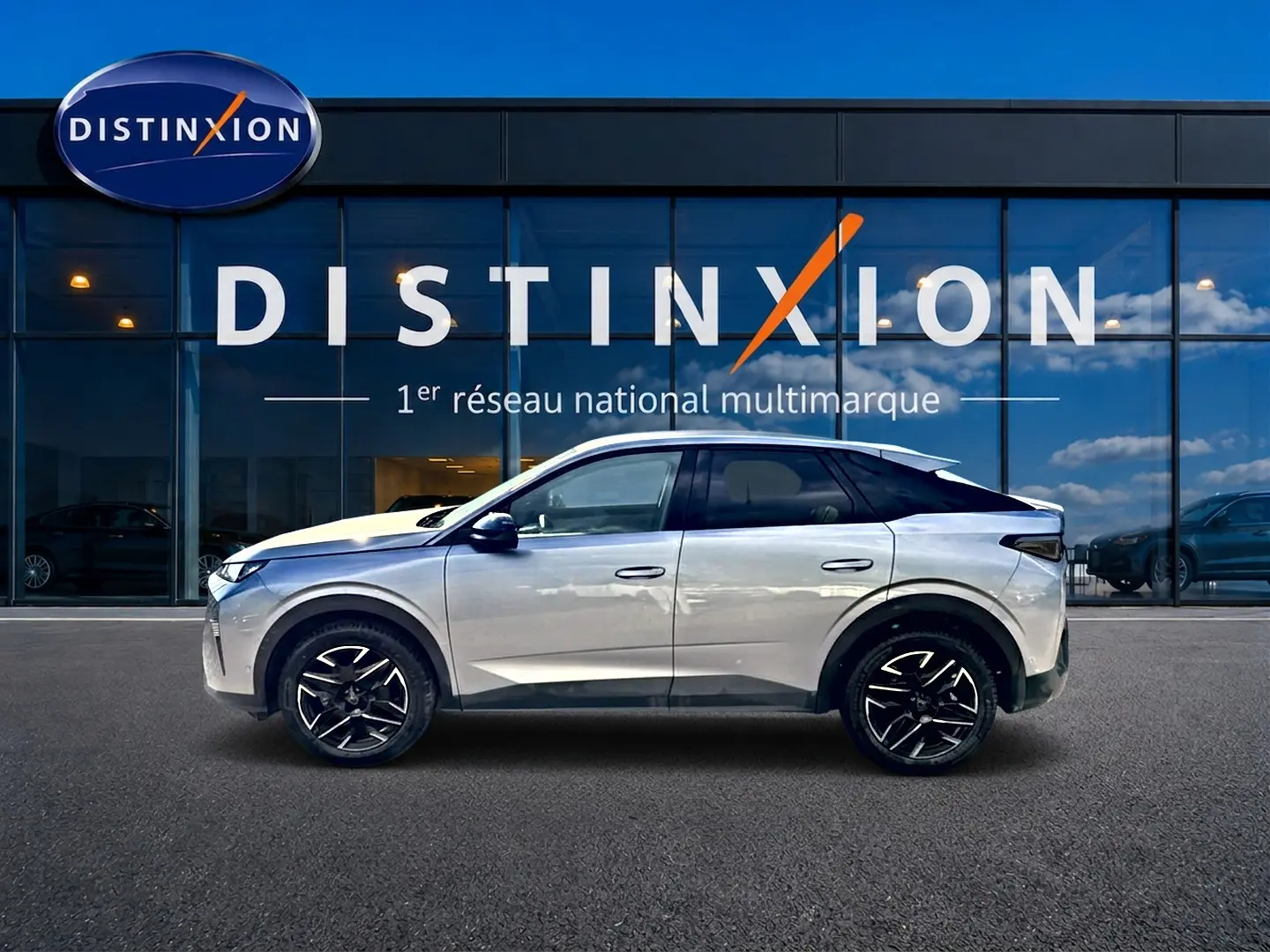 Profil côté gauche du Peugeot 3008 gris Artense avec toit noir et jantes alliage noires devant une vitrine Distinxion.