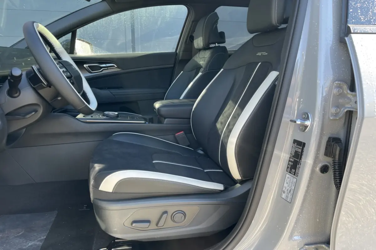 Vue intérieure côté conducteur du Kia Sportage gris céramique, sièges sport noirs avec surpiqûres blanches et logo GT.