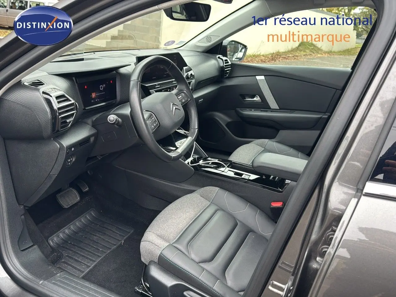 Intérieur côté conducteur d'une Citroën C4 gris toit noir, avec tableau de bord moderne et sièges cuir gris.