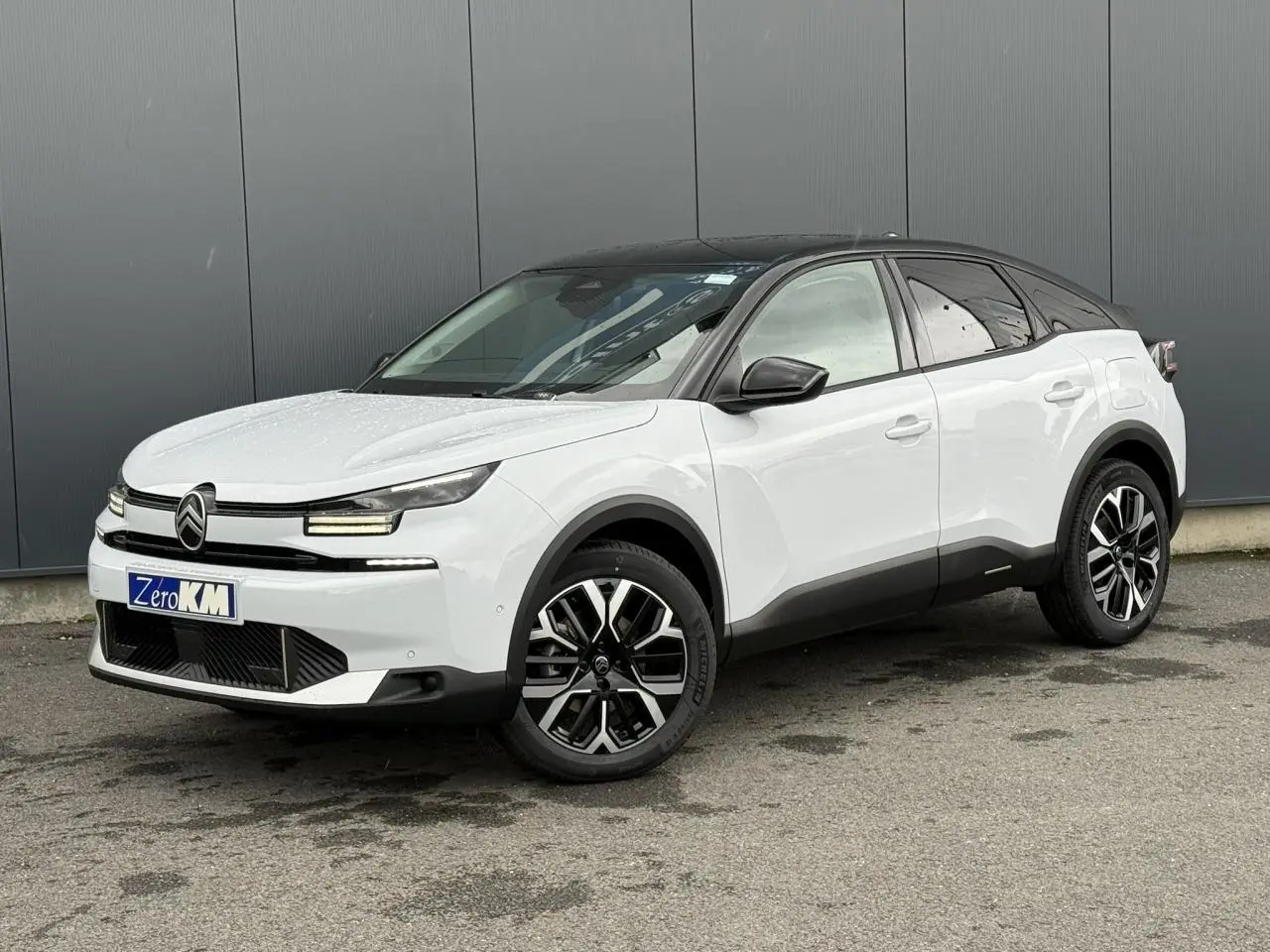 Citroën C4 hybride blanc Okénite avec toit noir, vue 3/4 avant droit, jantes alliage 18 pouces diamantées.