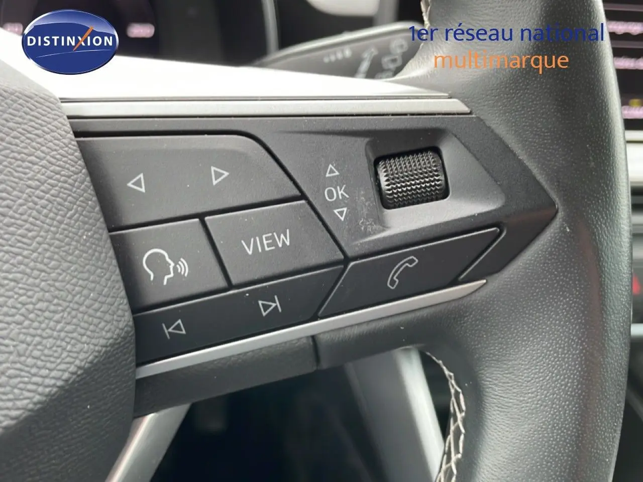 Gros plan sur les commandes au volant cuir noir de la SEAT LEON ST 2025, boutons multifonctions et molette tactile.