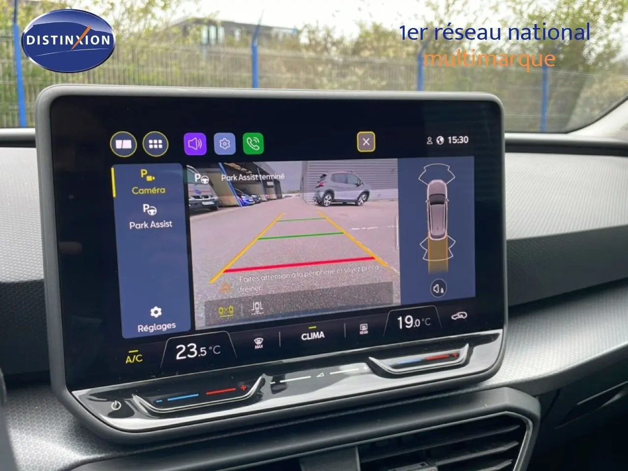 Vue rapprochée de l’écran tactile intérieur du SEAT LEON ST gris magnétique, affichant la caméra de recul et l’aide au stationnement.