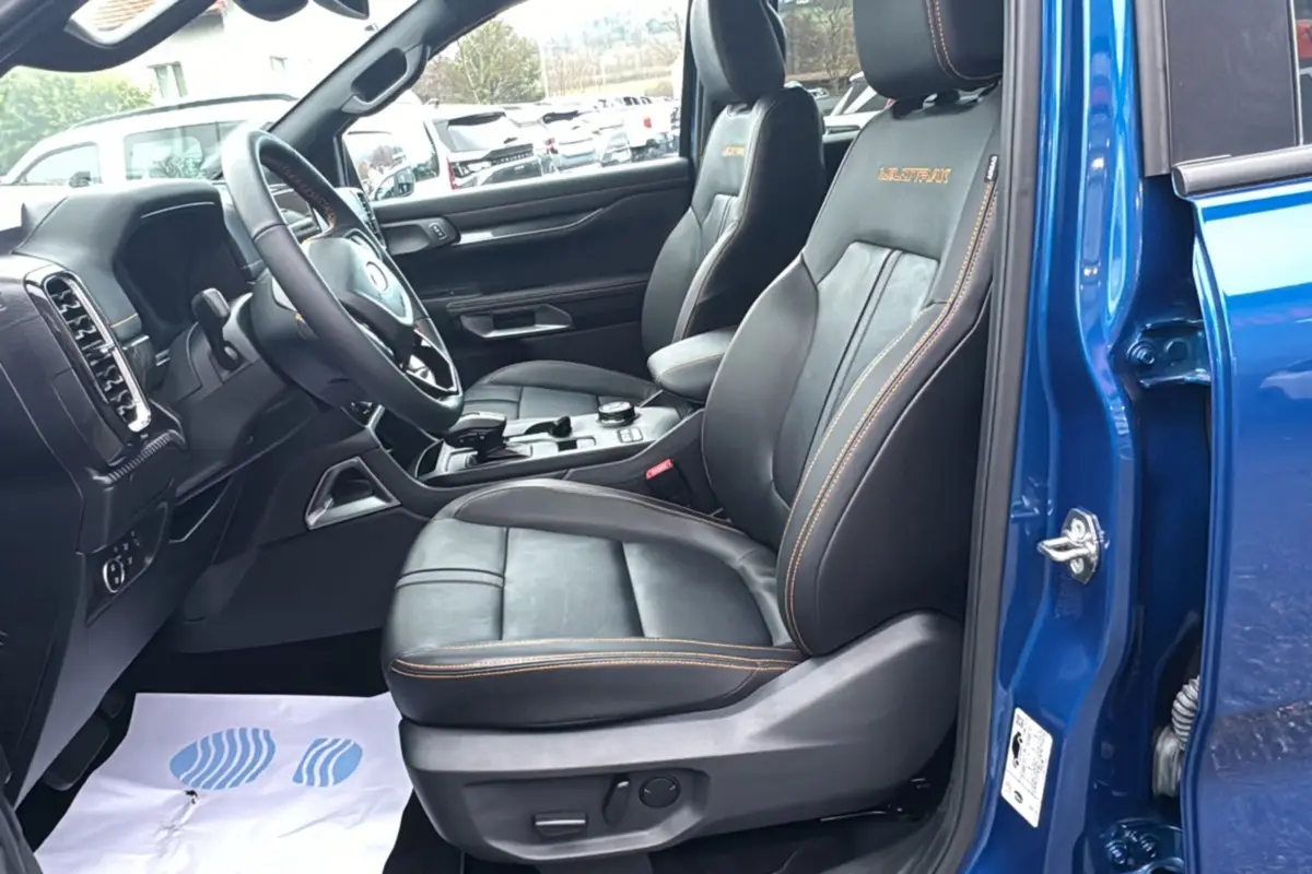 Vue intérieure côté conducteur du Ford Ranger 2025 bleu lightning, sièges cuir noirs avec surpiqûres orange Wildtrak.