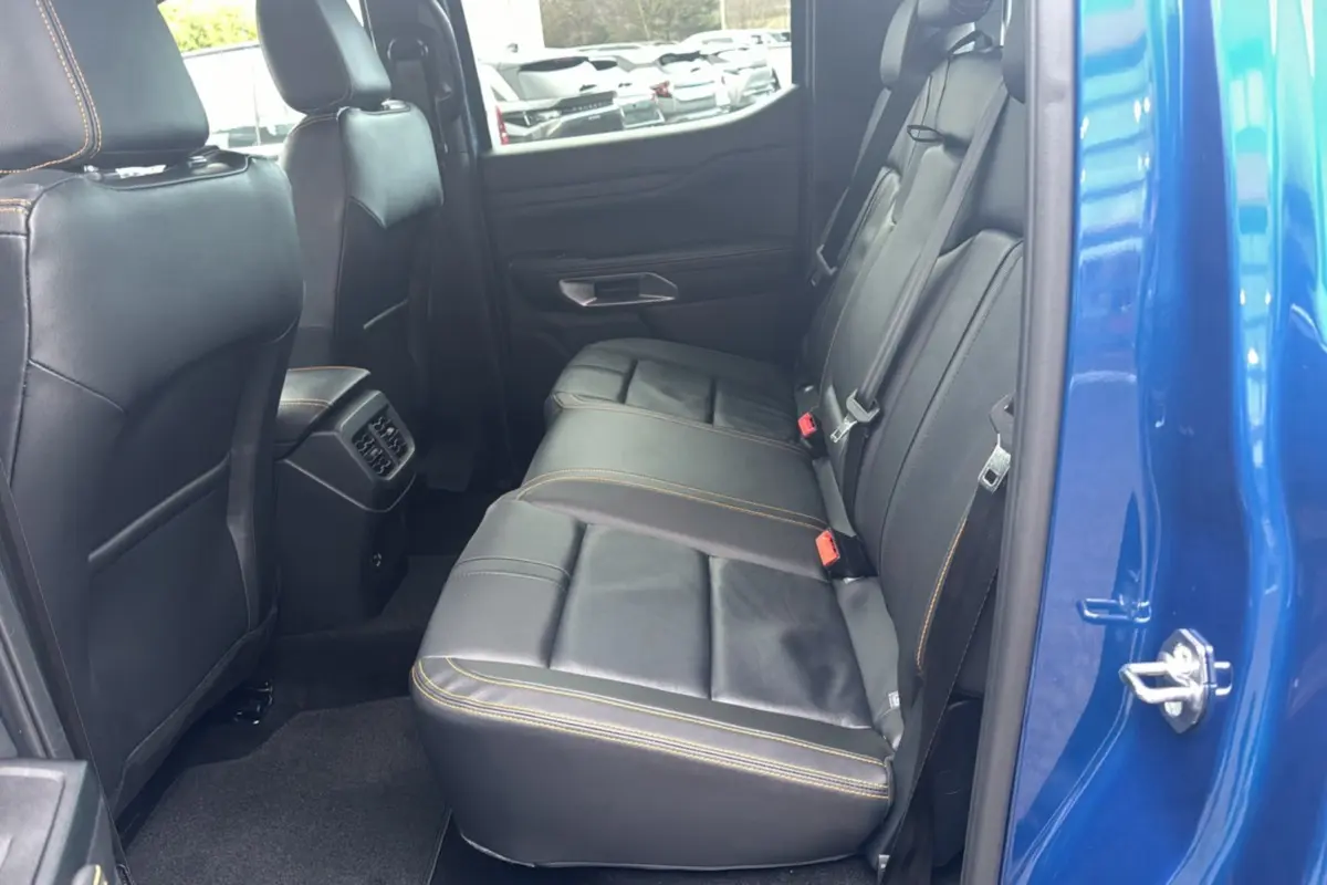 Vue côté droit de l'intérieur arrière du Ford Ranger 2025 bleu lightning avec sièges en cuir noir et surpiqûres orange.