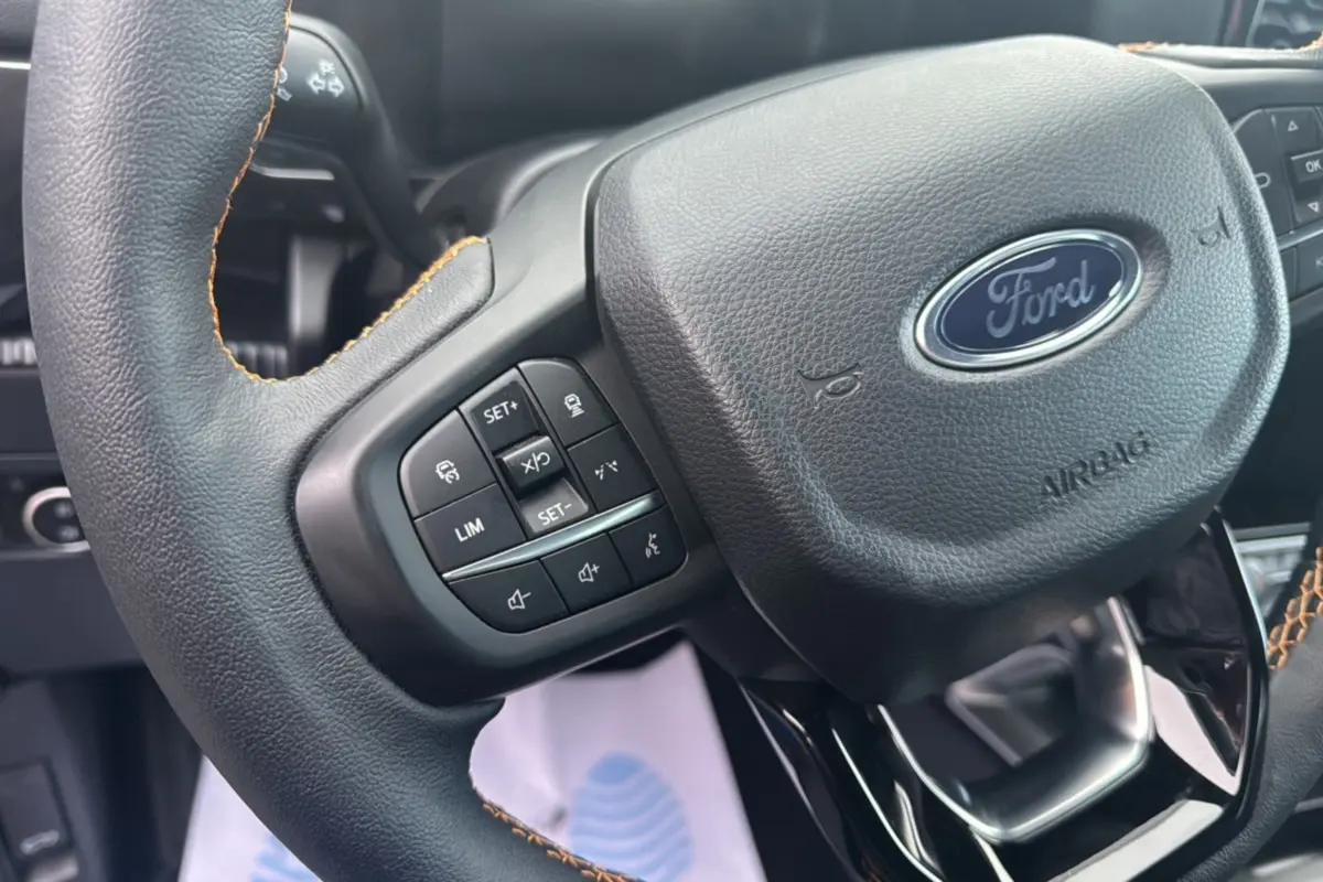 Gros plan sur le volant cuir noir avec commandes multifonctions du Ford Ranger 2025, version Wildtrak Plus.