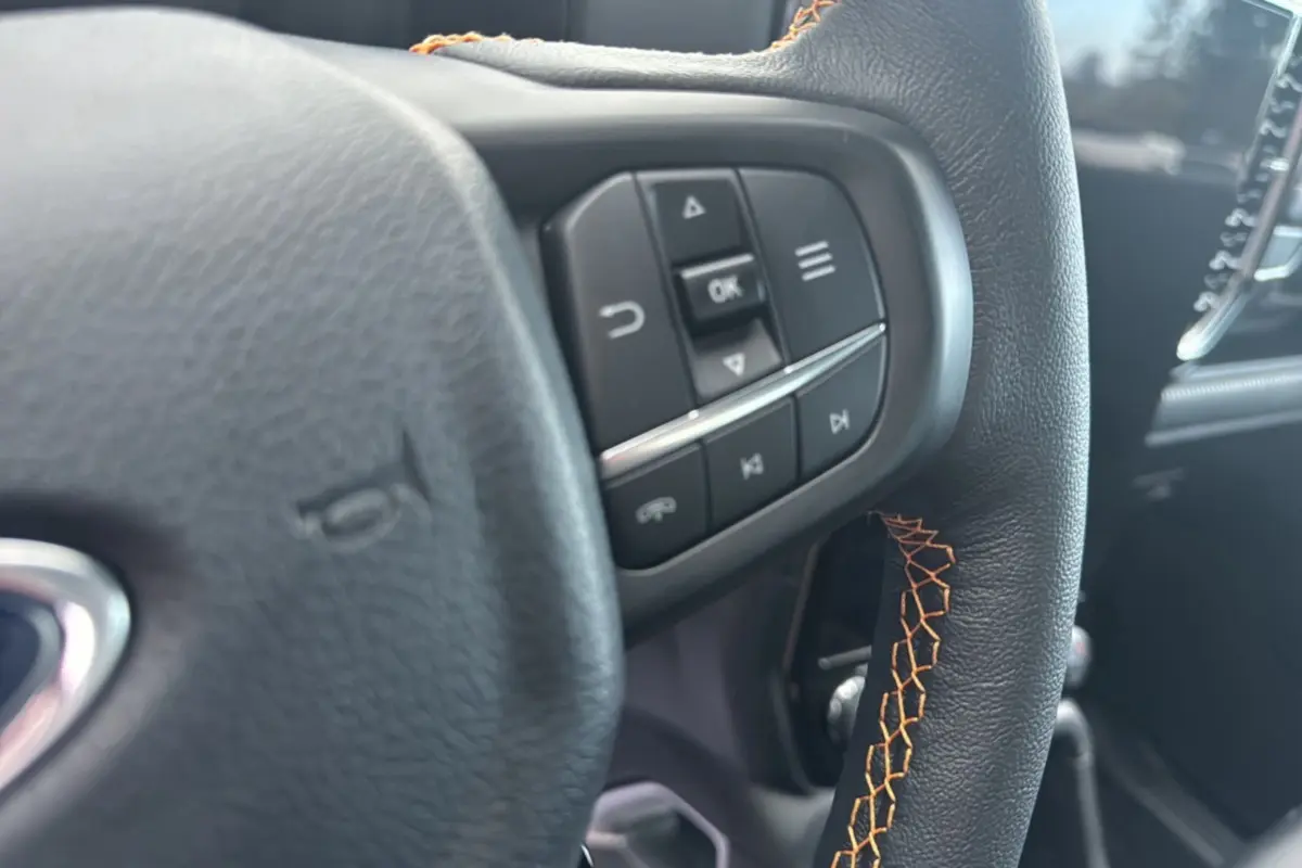 Gros plan sur le volant cuir noir avec surpiqûres orange et commandes multifonctions du Ford Ranger 2025.