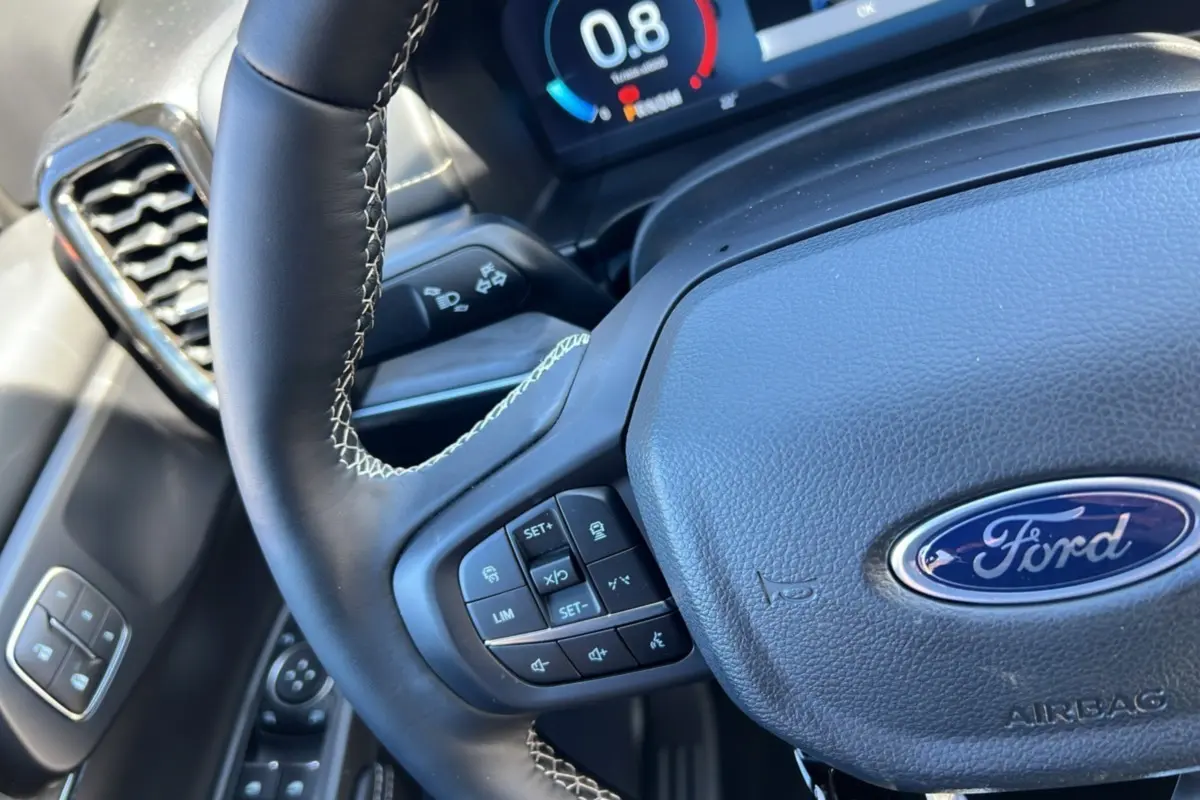 Gros plan sur le volant cuir multifonctions du Ford Ranger 2026, avec tableau de bord numérique en arrière-plan.