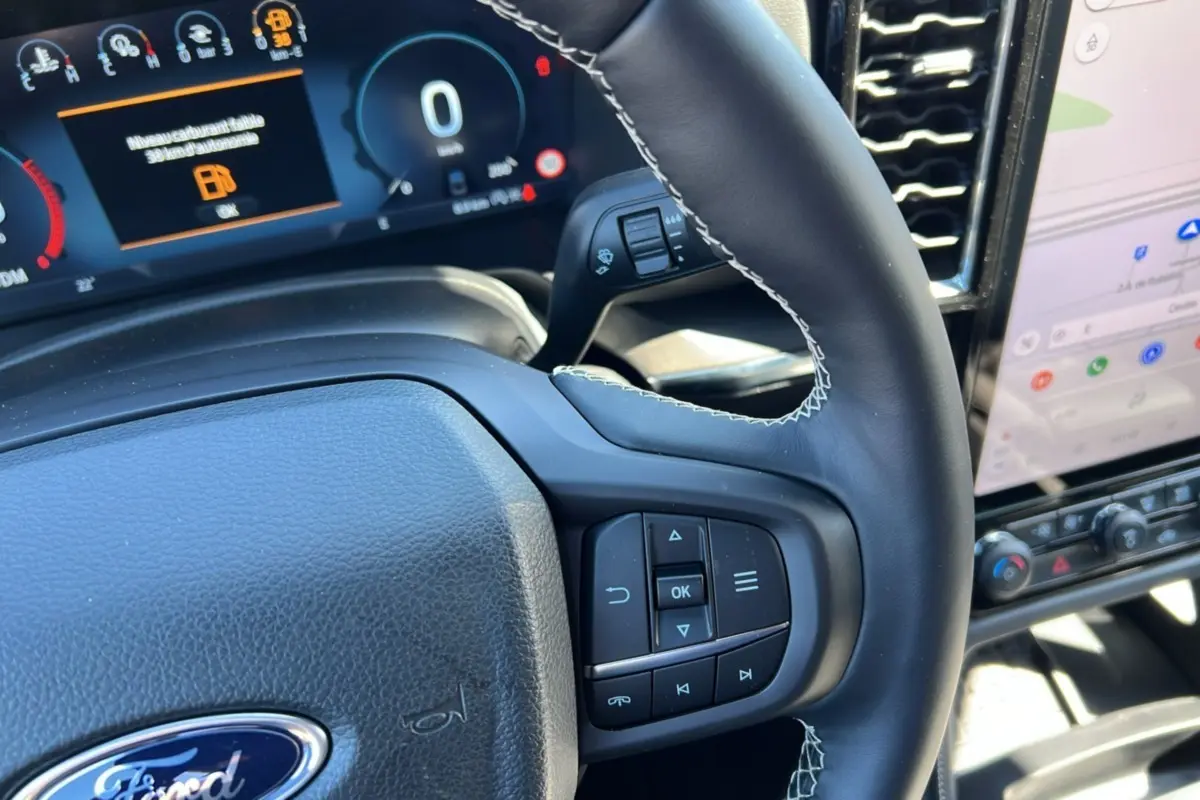 Gros plan sur le volant cuir noir du Ford Ranger 2026 avec commandes multifonctions et tableau de bord numérique.