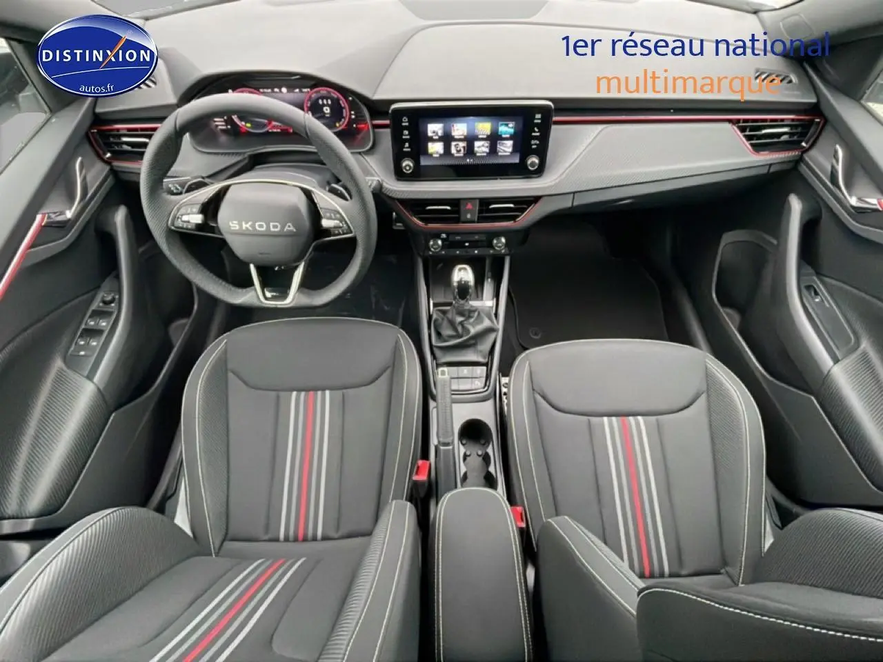 Vue intérieure avant du Skoda Kamiq blanc nacré 2026, avec tableau de bord moderne et sièges sport noirs à bandes rouges.