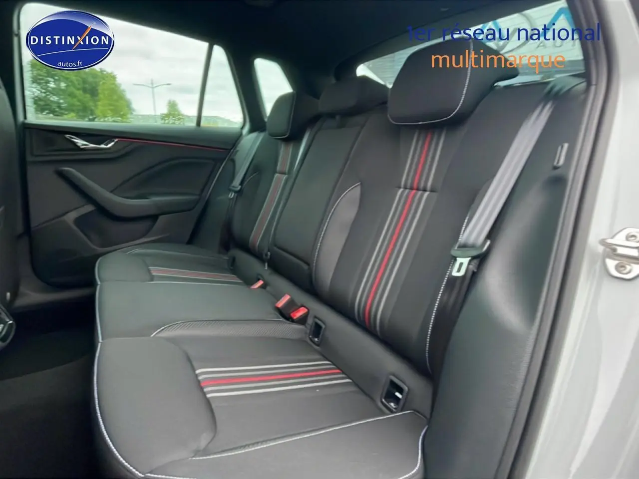 Vue intérieure côté droit sur la banquette arrière noire avec surpiqûres blanches et bandes rouges du Skoda Kamiq blanc nacré.