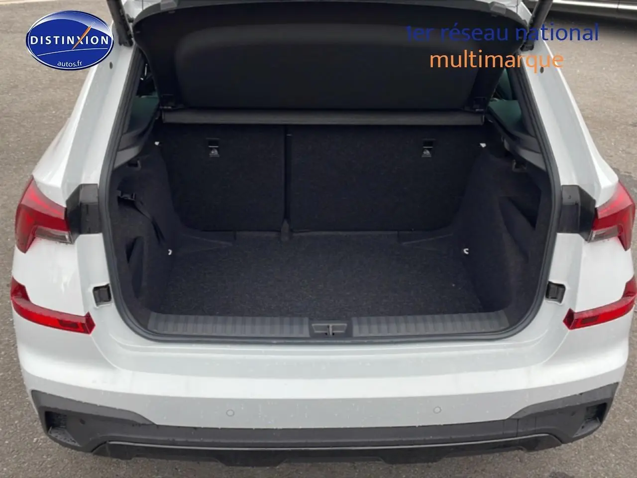Coffre ouvert vu de l'arrière d'un Skoda Kamiq blanc nacré avec hayon et feux arrière LED visibles.