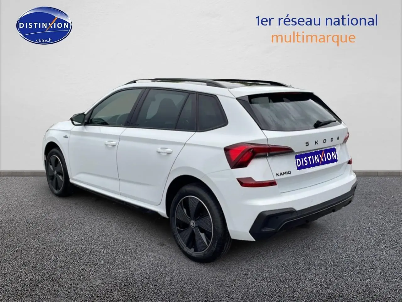 Vue 3/4 arrière droite d'un Skoda Kamiq blanc nacré avec jantes noires et toit panoramique en verre.