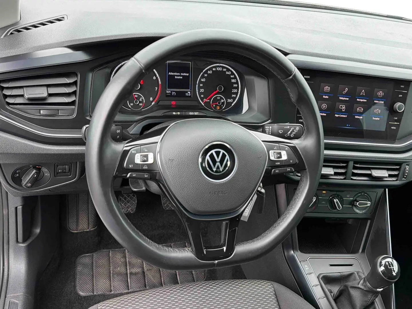Vue intérieure centrée sur le volant noir de la Volkswagen Polo Business 2021 avec tableau de bord et écran tactile.