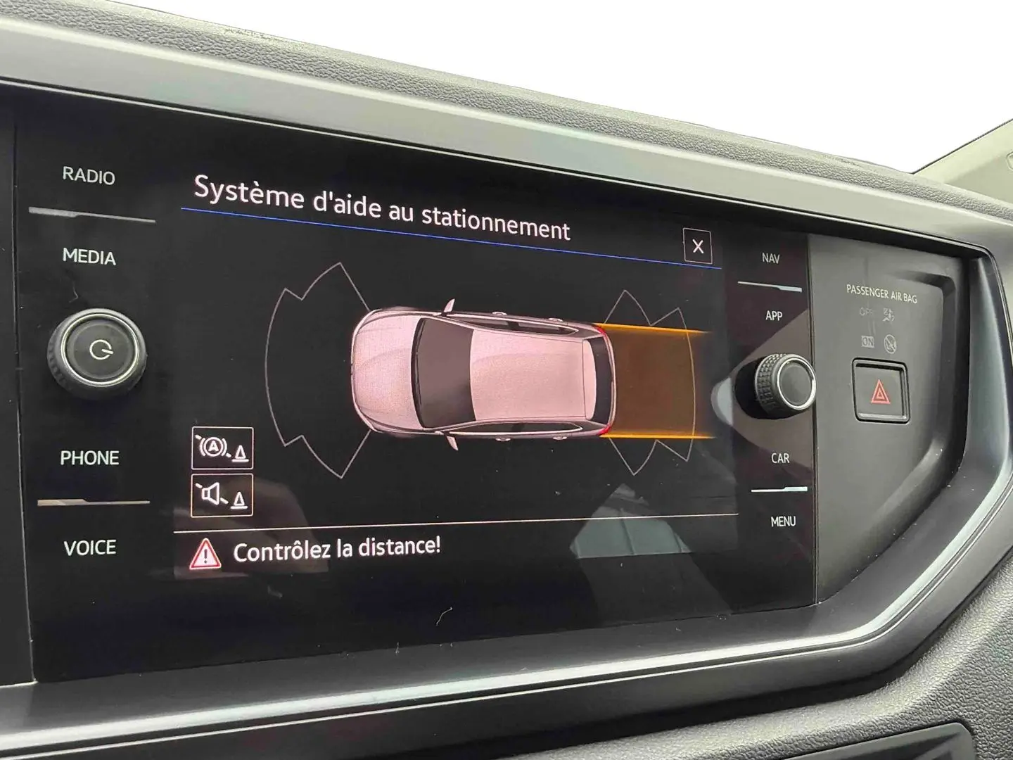 Écran central du système d'aide au stationnement de la Volkswagen Polo Business, affichant une vue aérienne du véhicule blanc.