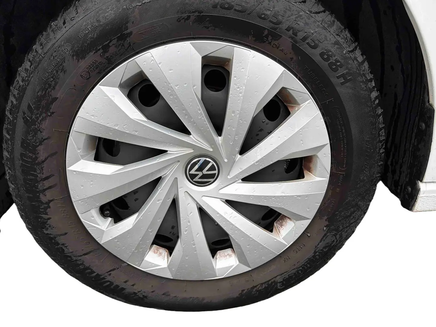 Gros plan sur la roue avant droite d'une Volkswagen Polo Business blanche avec enjoliveur en acier argenté et traces de rouille.