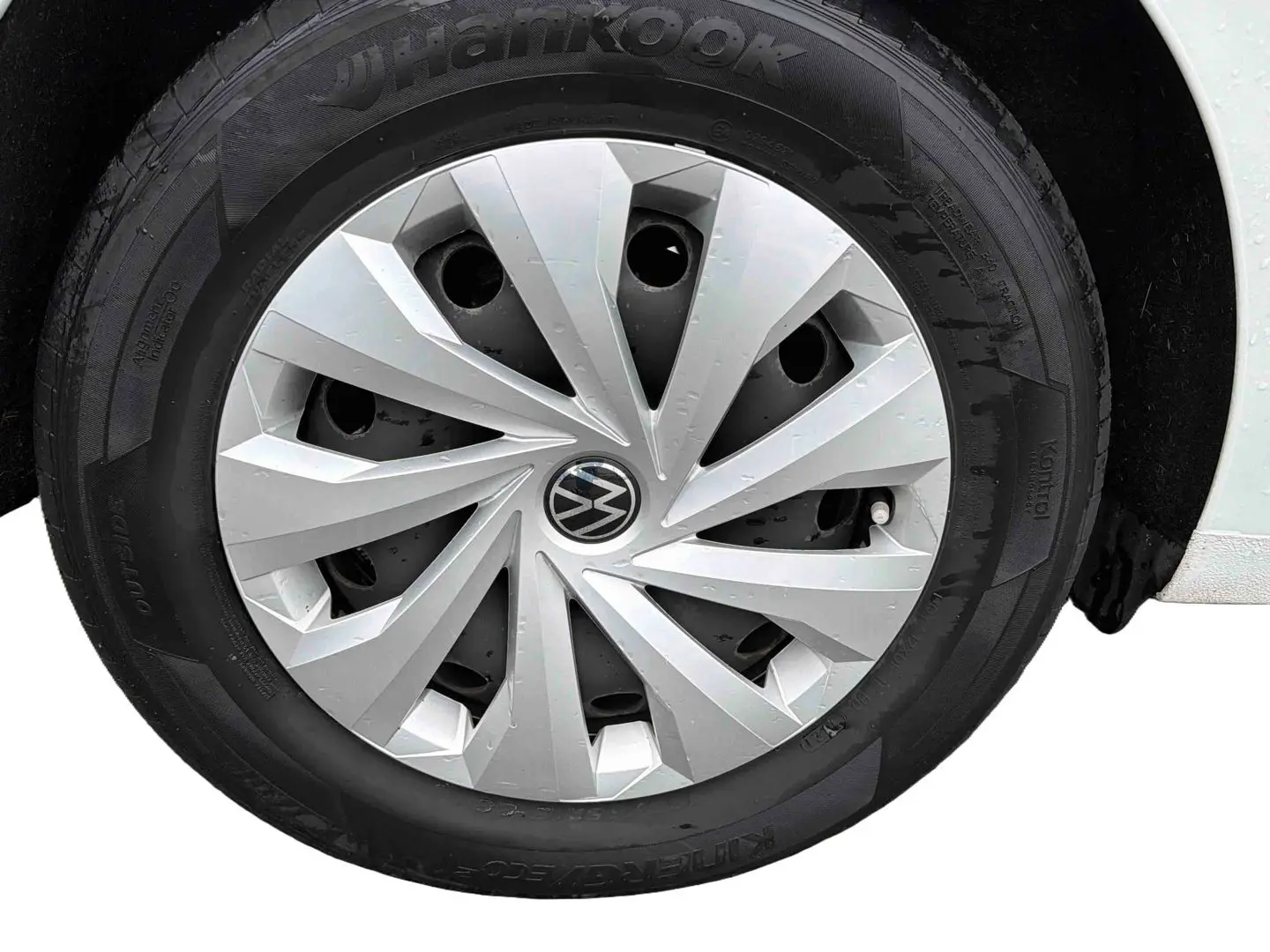 Gros plan sur la roue avant droite blanche d'une Volkswagen Polo Business 2021 avec enjoliveur argenté et logo VW central.