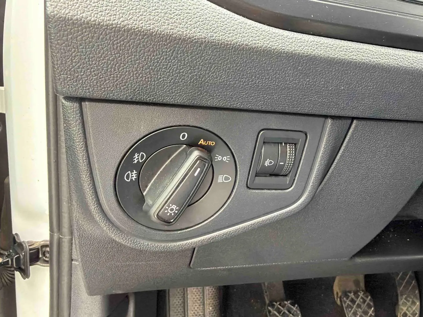Gros plan sur le sélecteur d'éclairage et le réglage de hauteur des phares dans une Volkswagen Polo Business blanche de 2021.