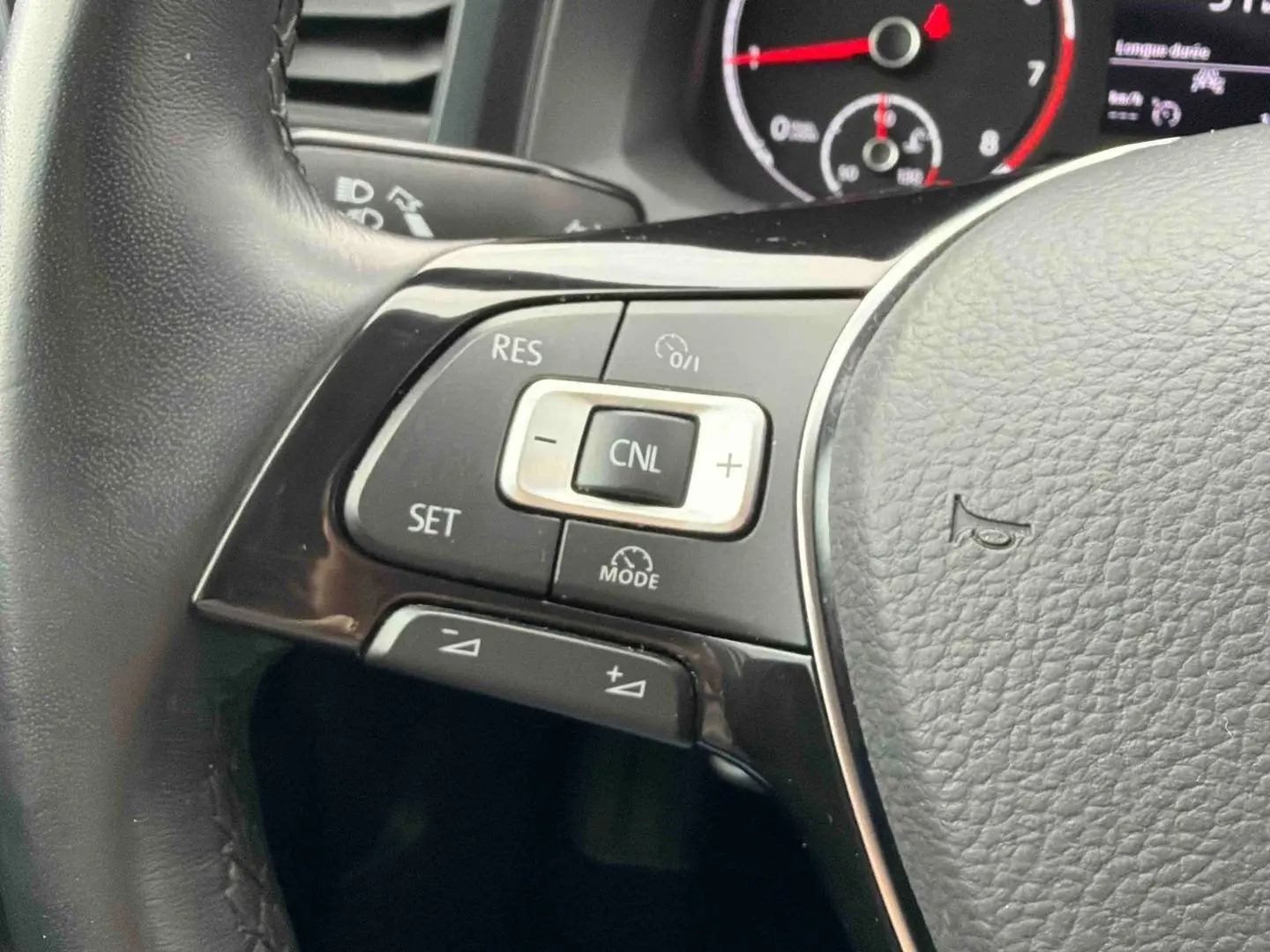 Gros plan sur les commandes du régulateur de vitesse au volant cuir noir de la Volkswagen Polo Business 2021.