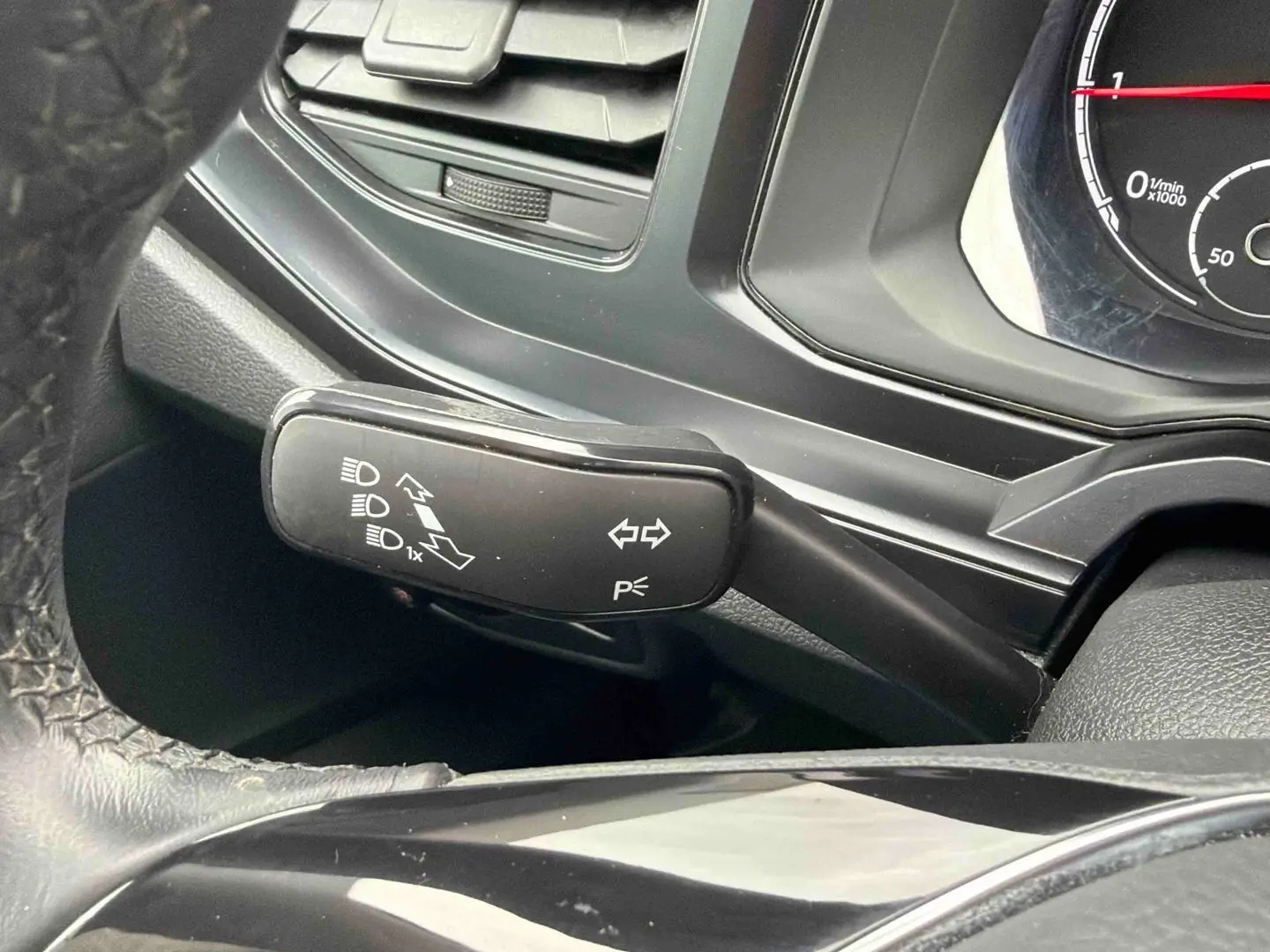 Gros plan sur la manette de clignotants noire à gauche du volant dans l’habitacle d’une Volkswagen Polo Business blanche.