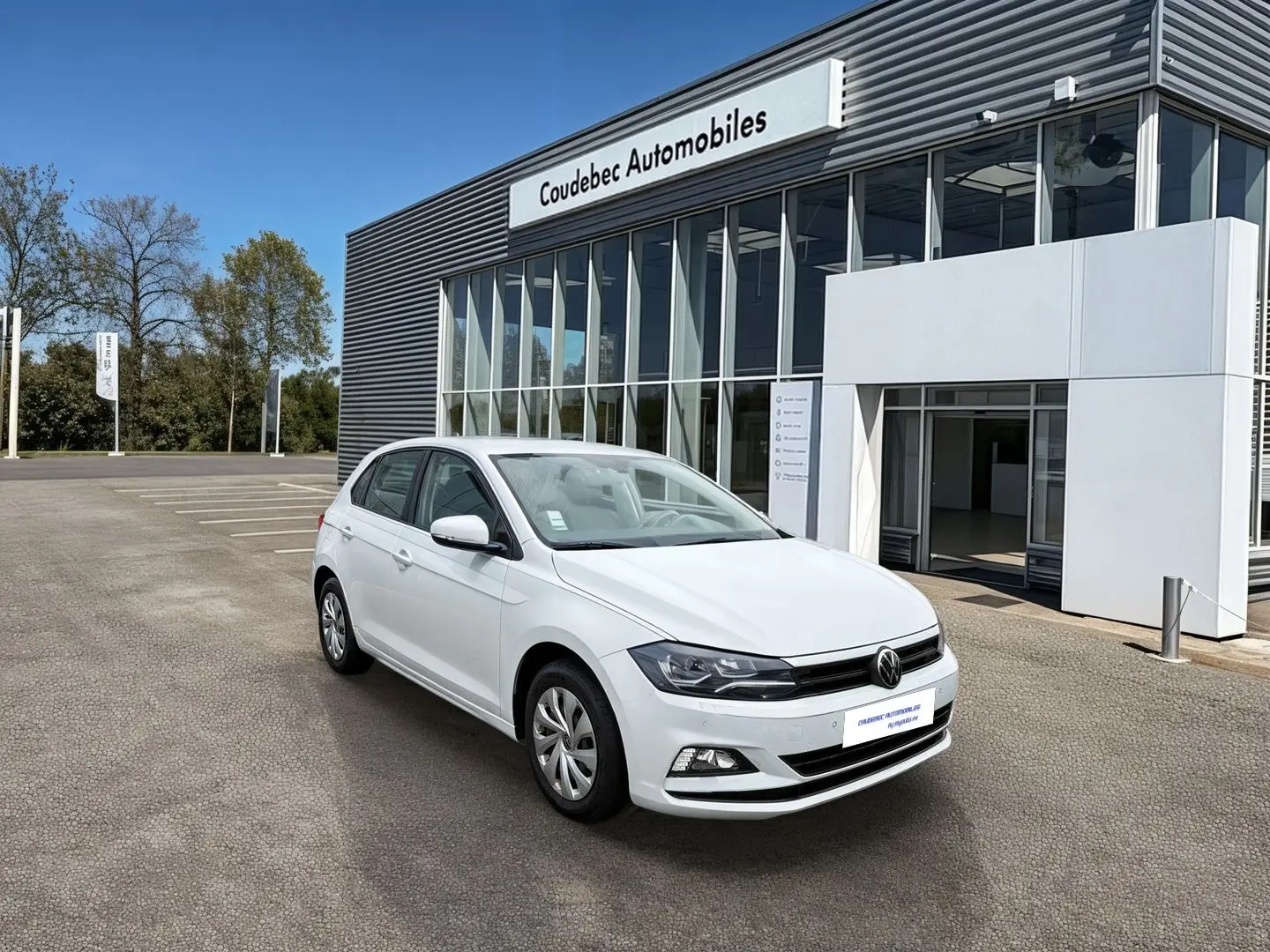 Volkswagen Polo Business blanche vue en 3/4 avant droit devant un bâtiment de concession.