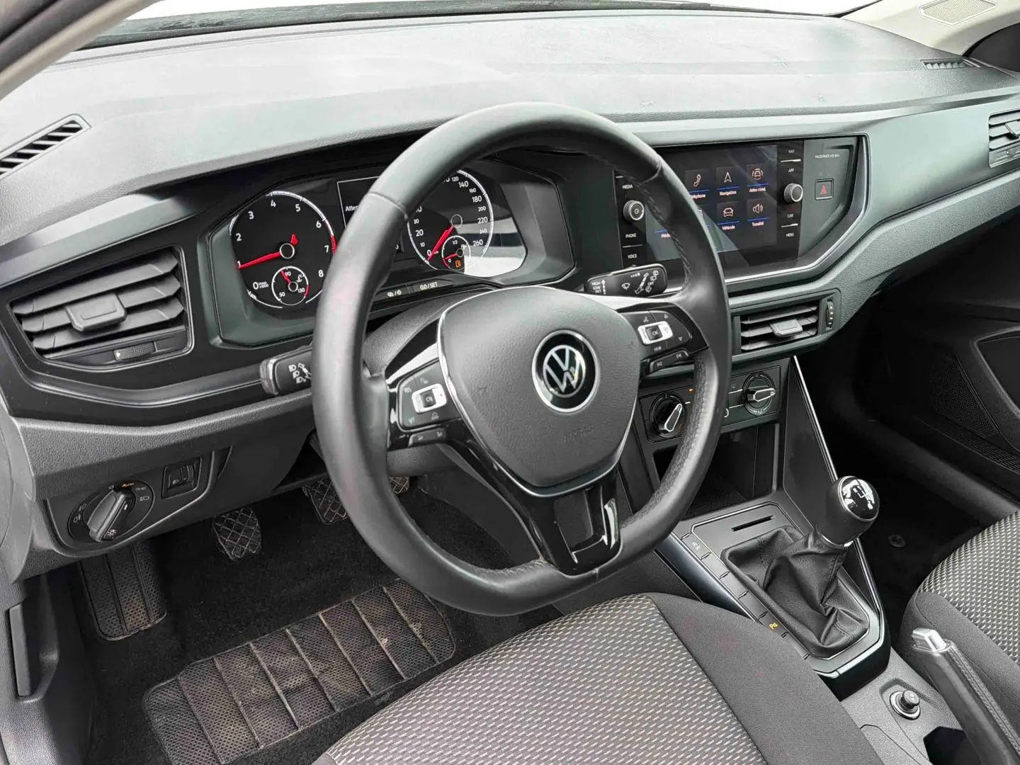 Vue intérieure côté conducteur du tableau de bord et volant noir de la Volkswagen Polo Business 2021 avec boîte manuelle.