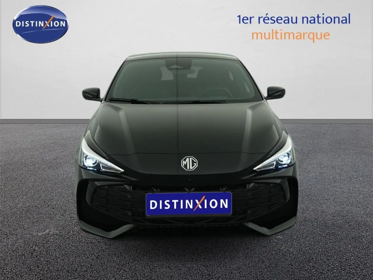Vue frontale d'une MG3 1.5 Hybrid+ noire, avec phares LED allumés et calandre imposante en arrière-plan neutre.