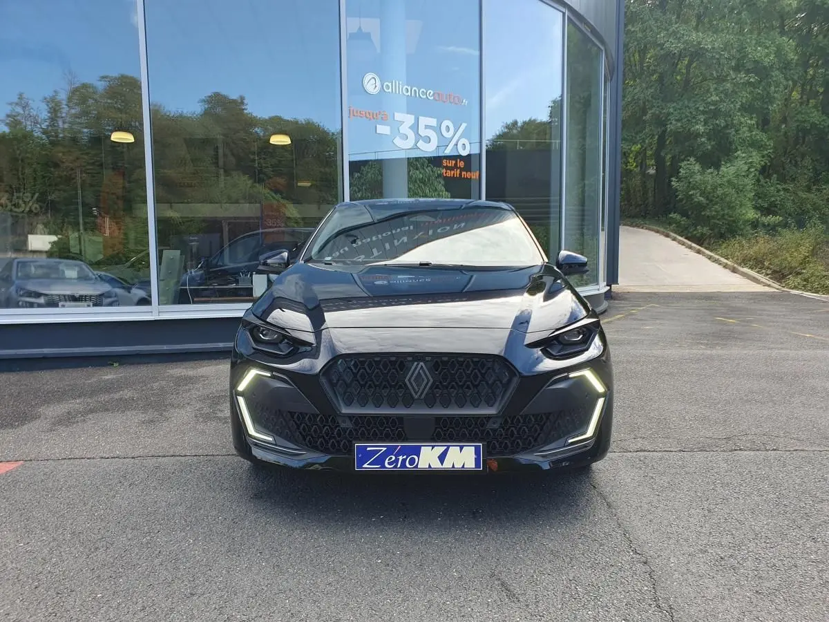 Vue avant d'une Renault Clio VI noire étoile avec feux LED allumés, calandre hexagonale et plaque "Zéro KM" visible.