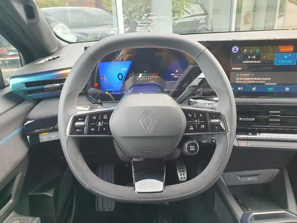 Vue intérieure centrée sur le volant multifonction de la Renault Clio VI avec tableau de bord numérique et écran tactile.
