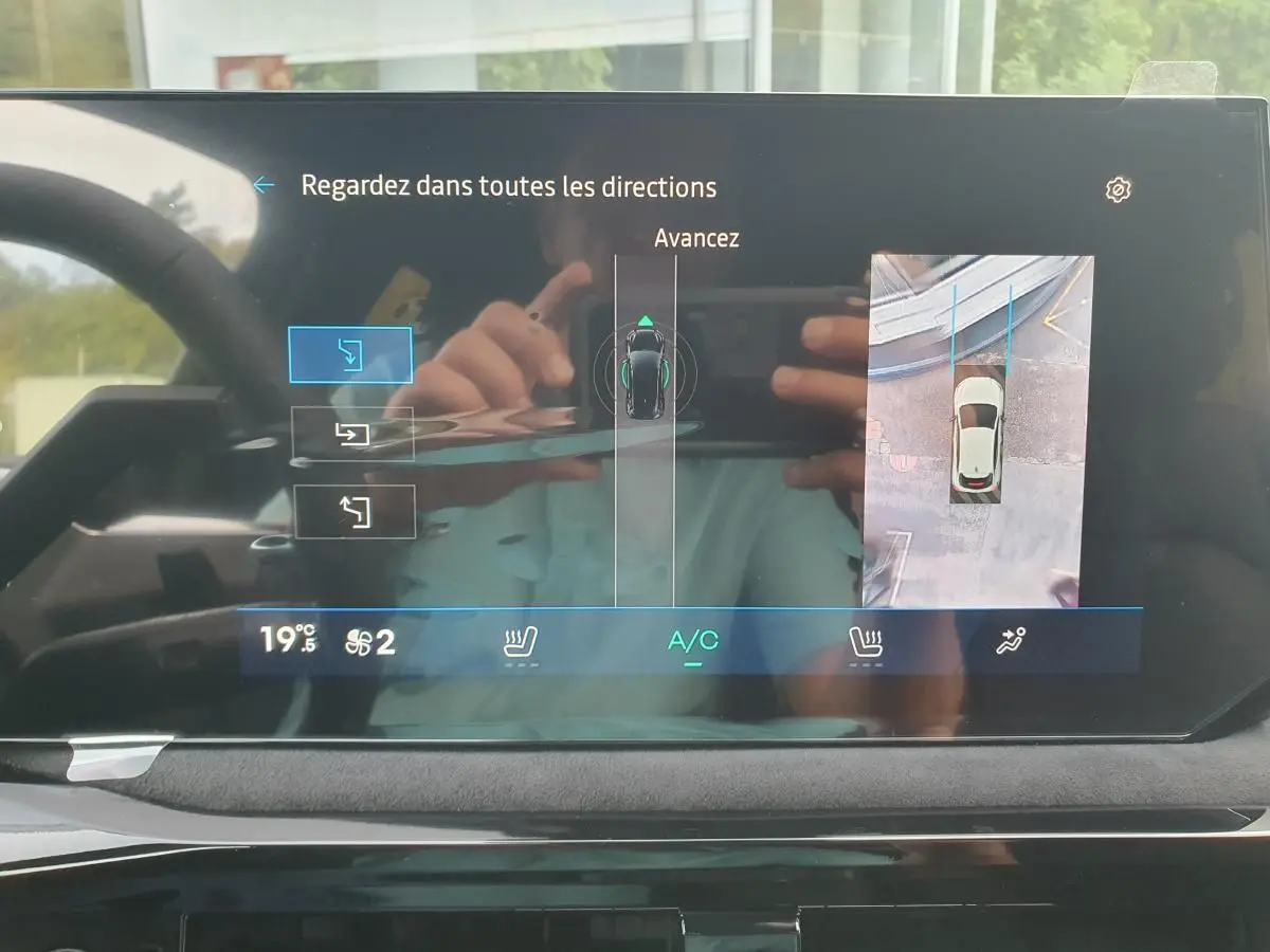 Écran tactile intérieur montrant l’aide au parking avec vue 360° et caméra de recul de la Renault Clio VI noire étoile.