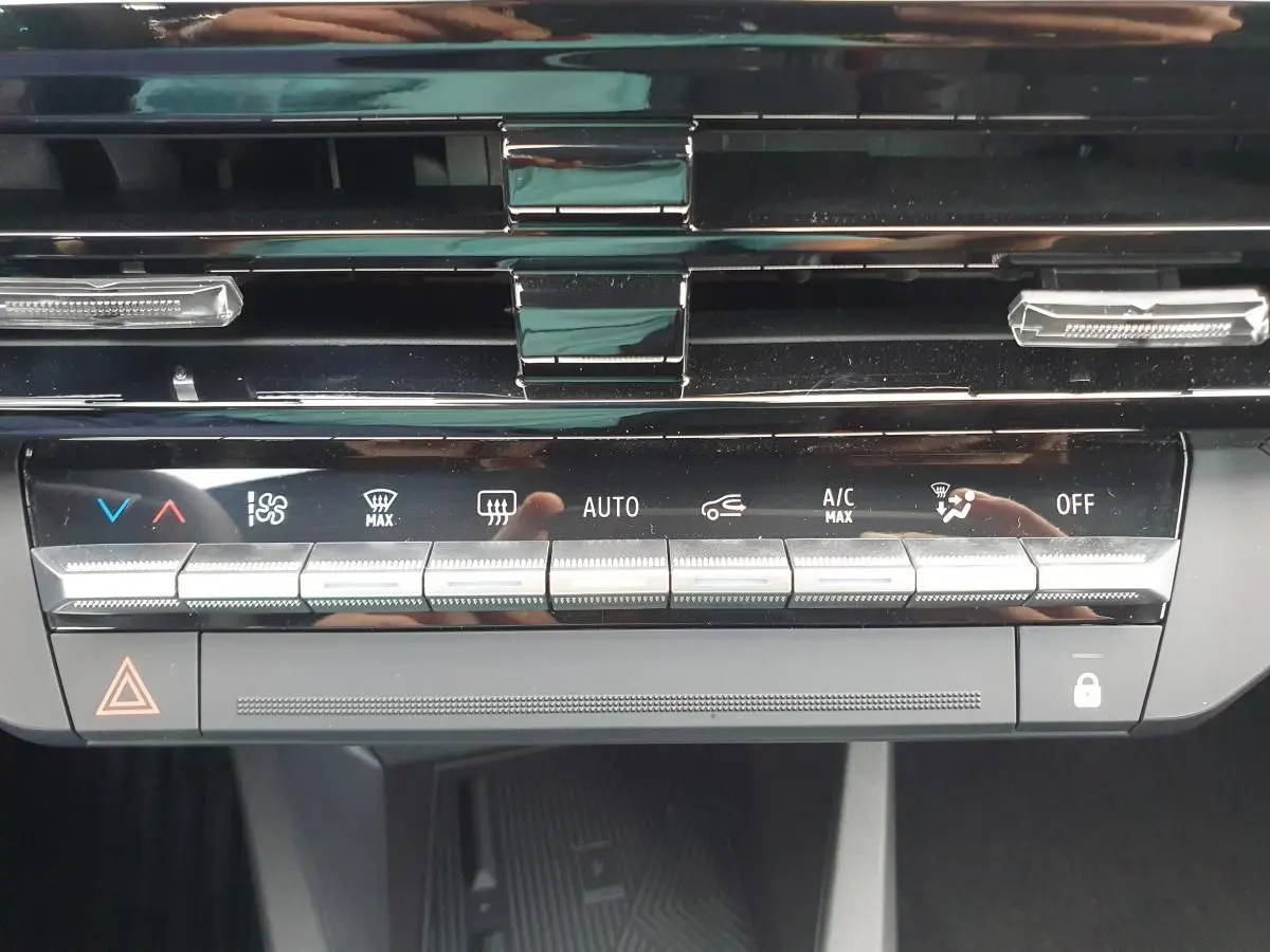 Vue rapprochée du tableau de bord noir de la Renault Clio VI montrant les commandes de climatisation et sécurité.