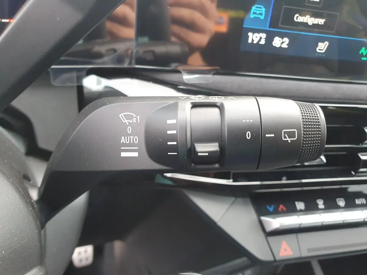 Gros plan sur la commande des essuie-glaces à gauche du volant dans l’habitacle de la Renault Clio VI noire étoile.