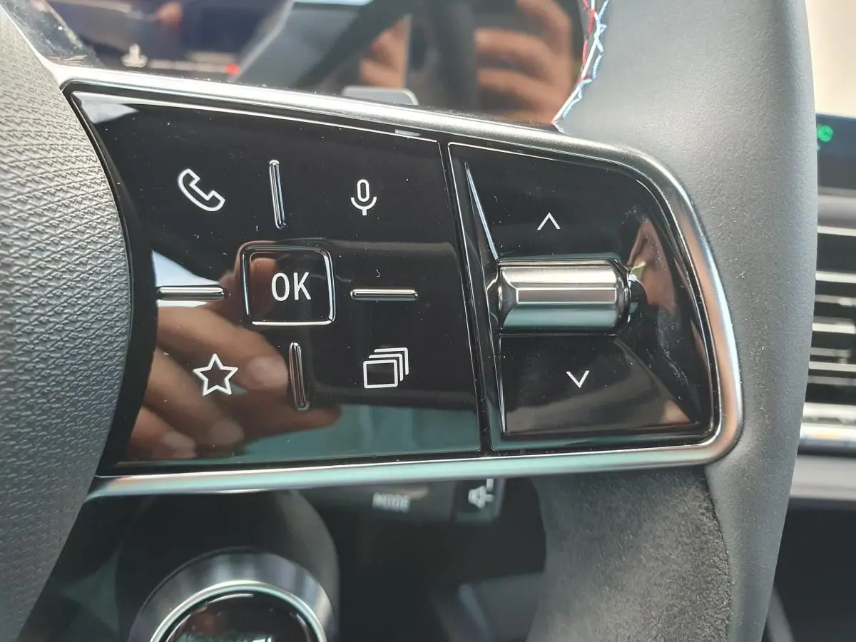 Gros plan sur les commandes multifonctions à droite du volant de la Renault Clio VI noire étoile, avec molette et boutons tactiles.