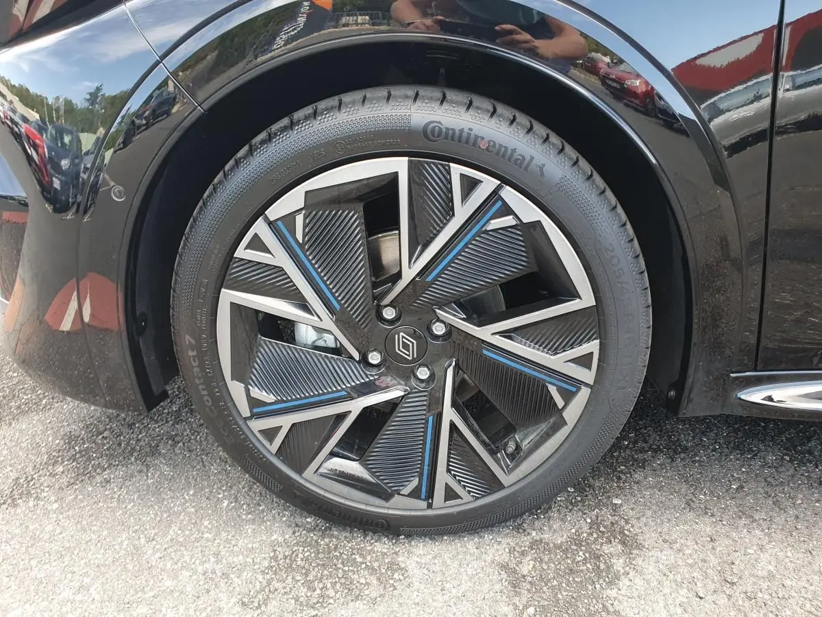 Gros plan sur la jante alliage diamantée 18” cosmic noire et argent avec touches bleues de la Renault Clio VI noire étoile.