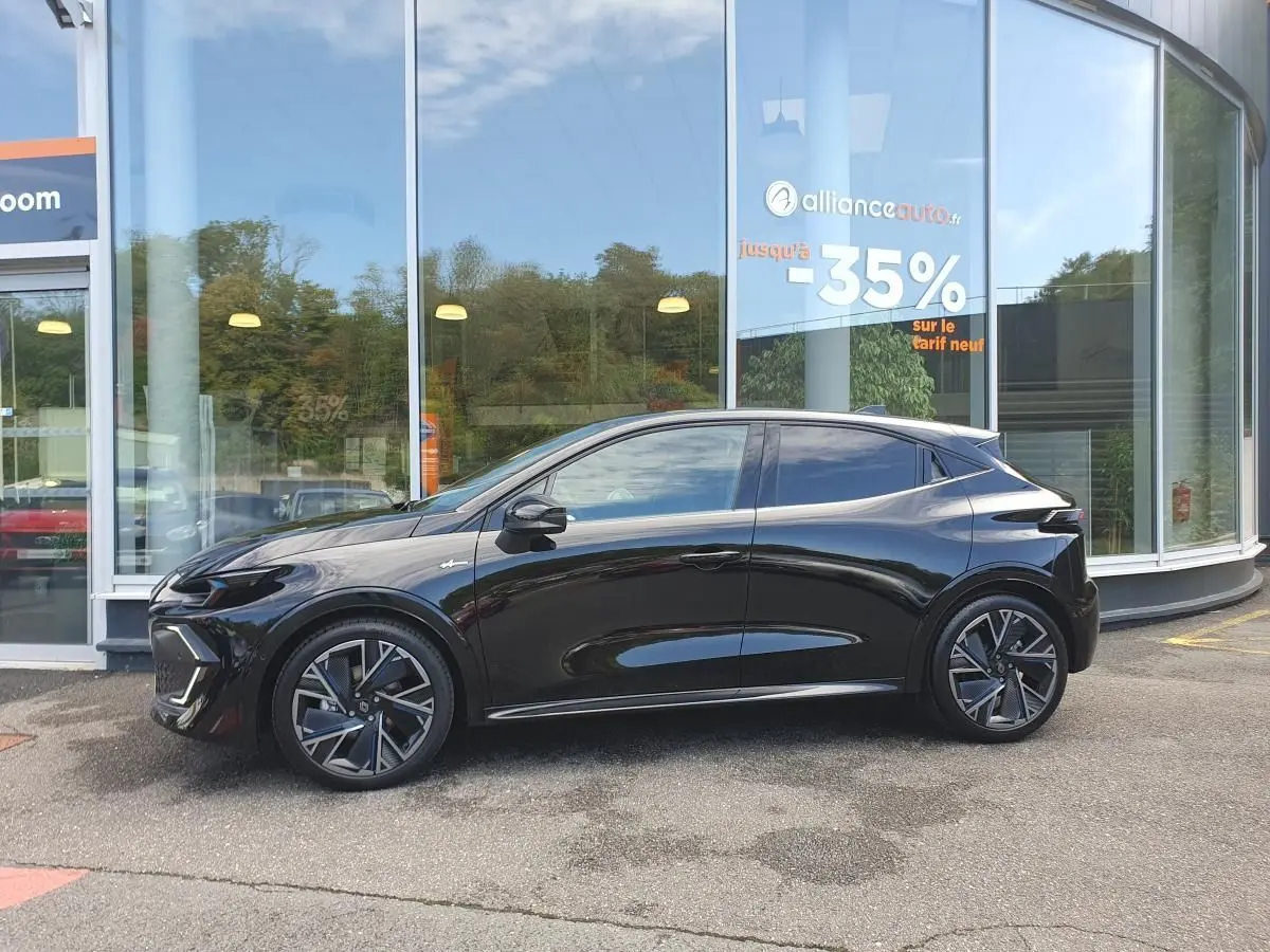 Profil droit d’une Renault Clio VI noire étoile avec jantes alliage diamantées 18” cosmic, stationnée devant une vitrine.