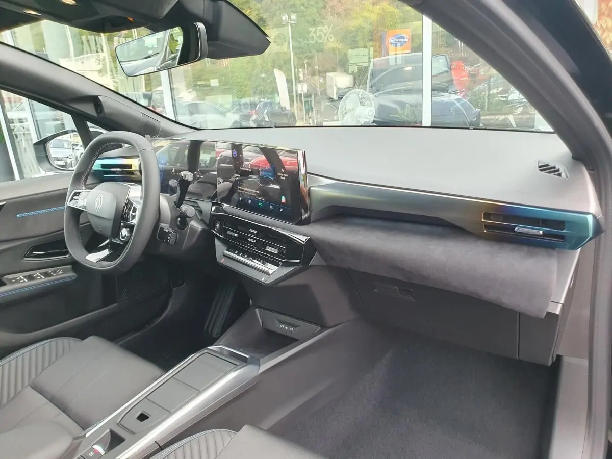 Intérieur avant de la Renault Clio VI noire étoile, vue côté passager avec tableau de bord moderne et écran tactile central.