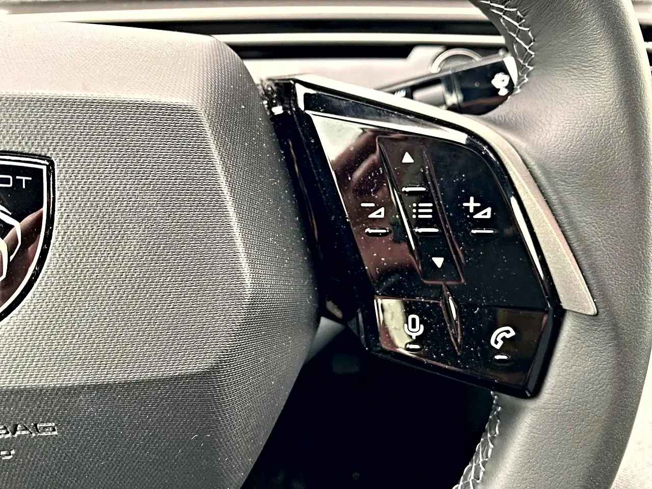 Gros plan sur le côté droit du volant cuir multifonction du Peugeot 3008 bleu obsession, avec commandes audio et téléphone.