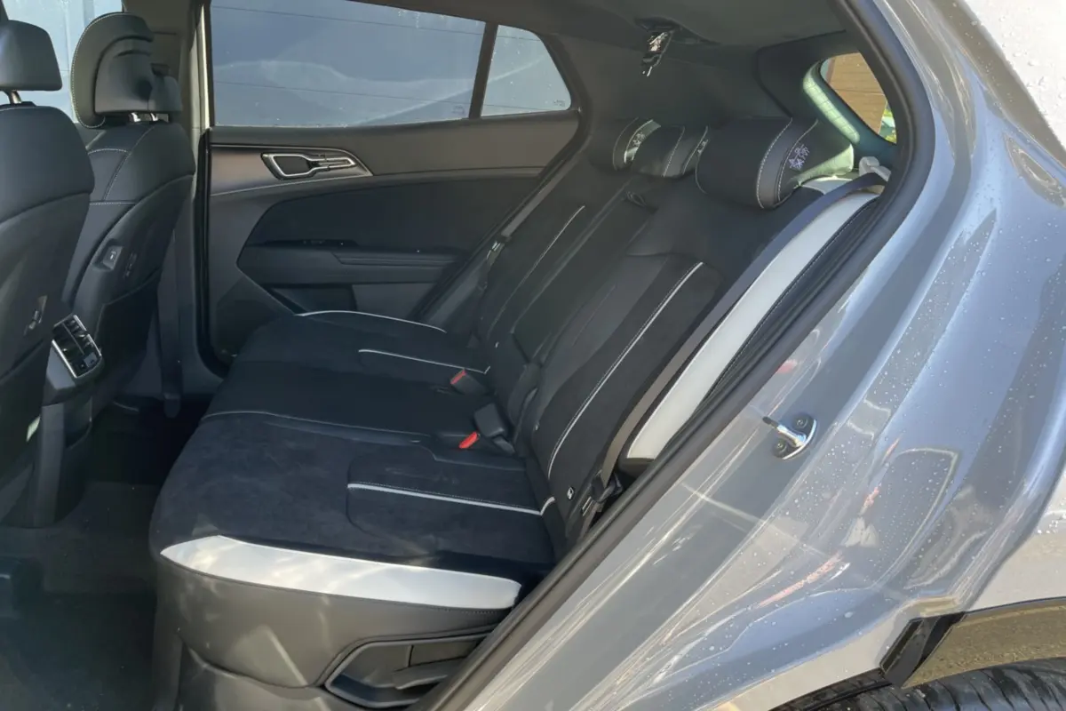 Vue côté gauche de l’habitacle arrière du Kia Sportage gris céramique, sièges noirs avec surpiqûres blanches.