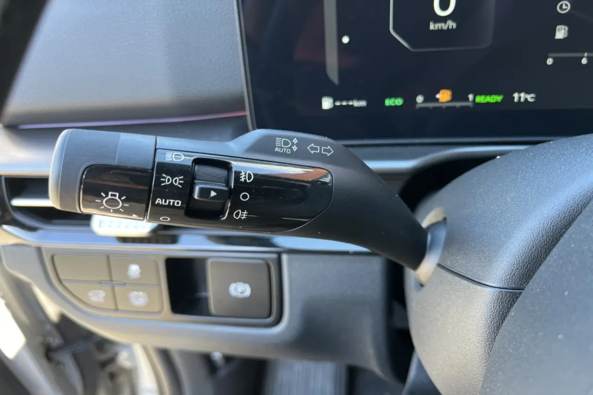 Gros plan sur la commande des feux et clignotants du Kia Sportage 2026, intérieur noir avec tableau de bord numérique.