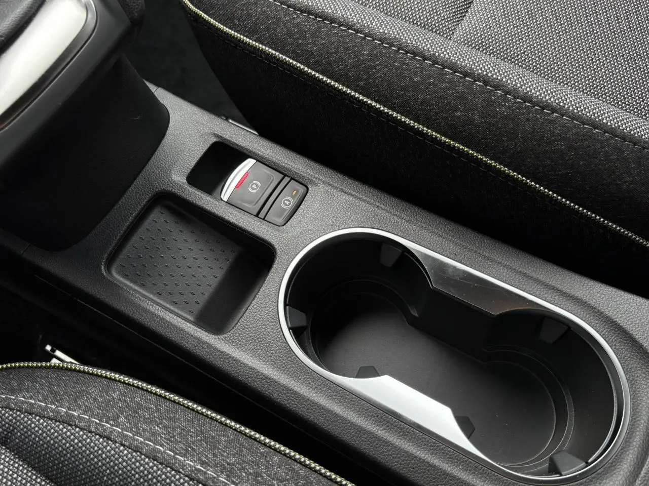Gros plan sur la console centrale noire du Renault Captur 2025 avec porte-gobelets et frein à main électrique.