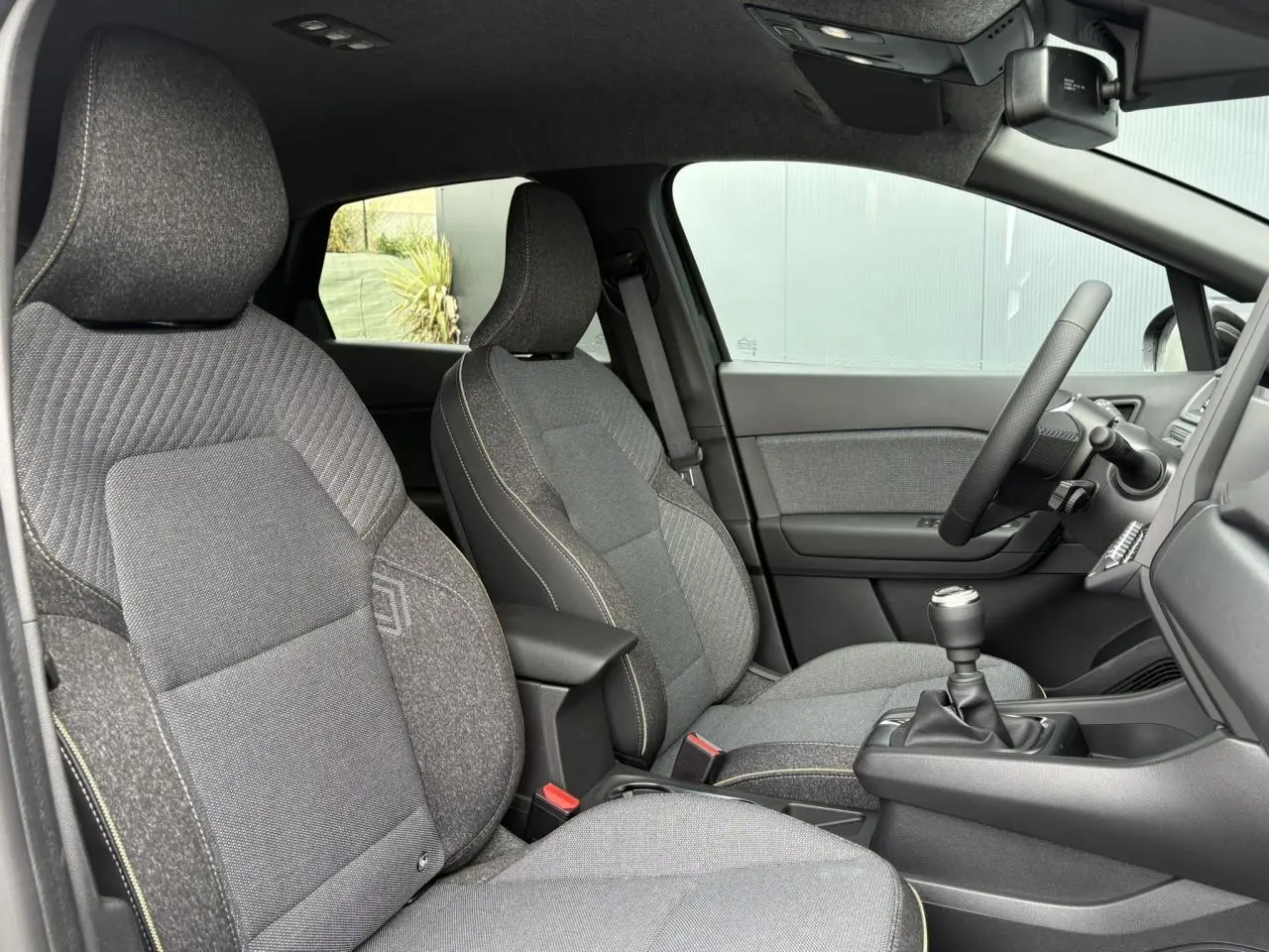 Vue intérieure côté gauche du Renault Captur 2025 Eco-G 100 Techno, sièges gris texturés et volant multifonction.