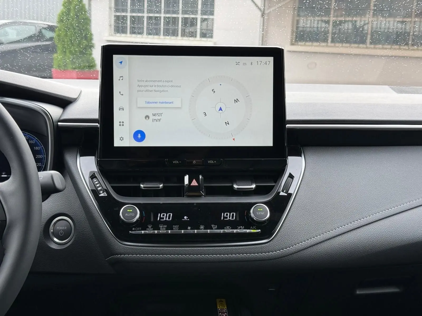 Tableau de bord de Toyota Corolla Touring Sport 2025 avec écran tactile central affichant une boussole et commandes climatisation.