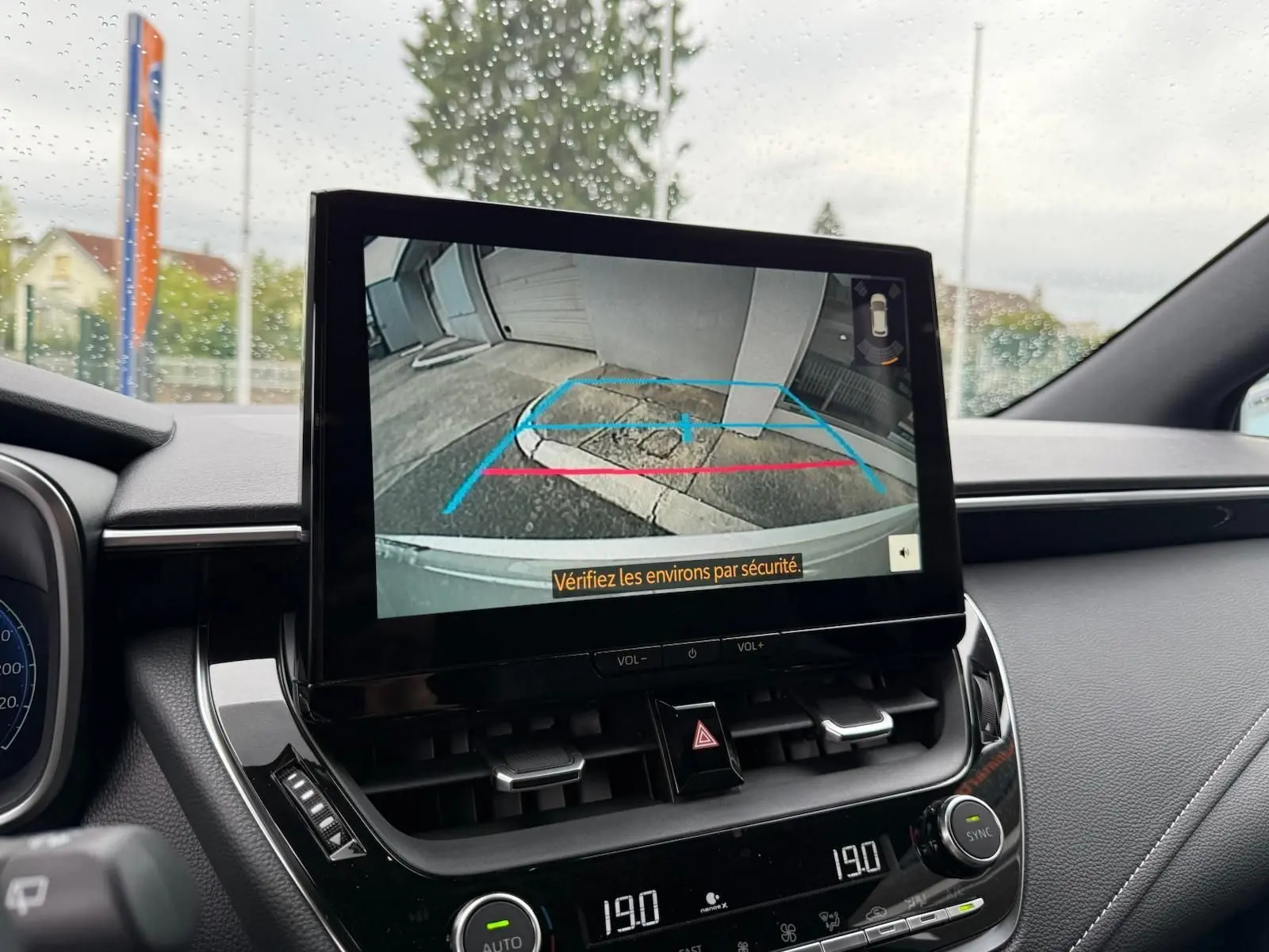 Écran central de la Toyota Corolla Touring Sport 2025 affichant la caméra de recul avec vue arrière et consignes de sécurité.