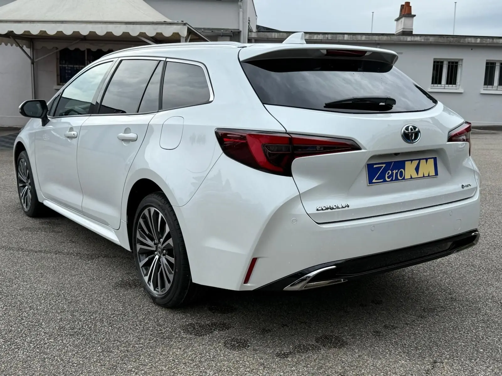 Toyota Corolla Touring Sport blanc lunaire nacré vue 3/4 arrière droit avec feux LED et jantes alliage.