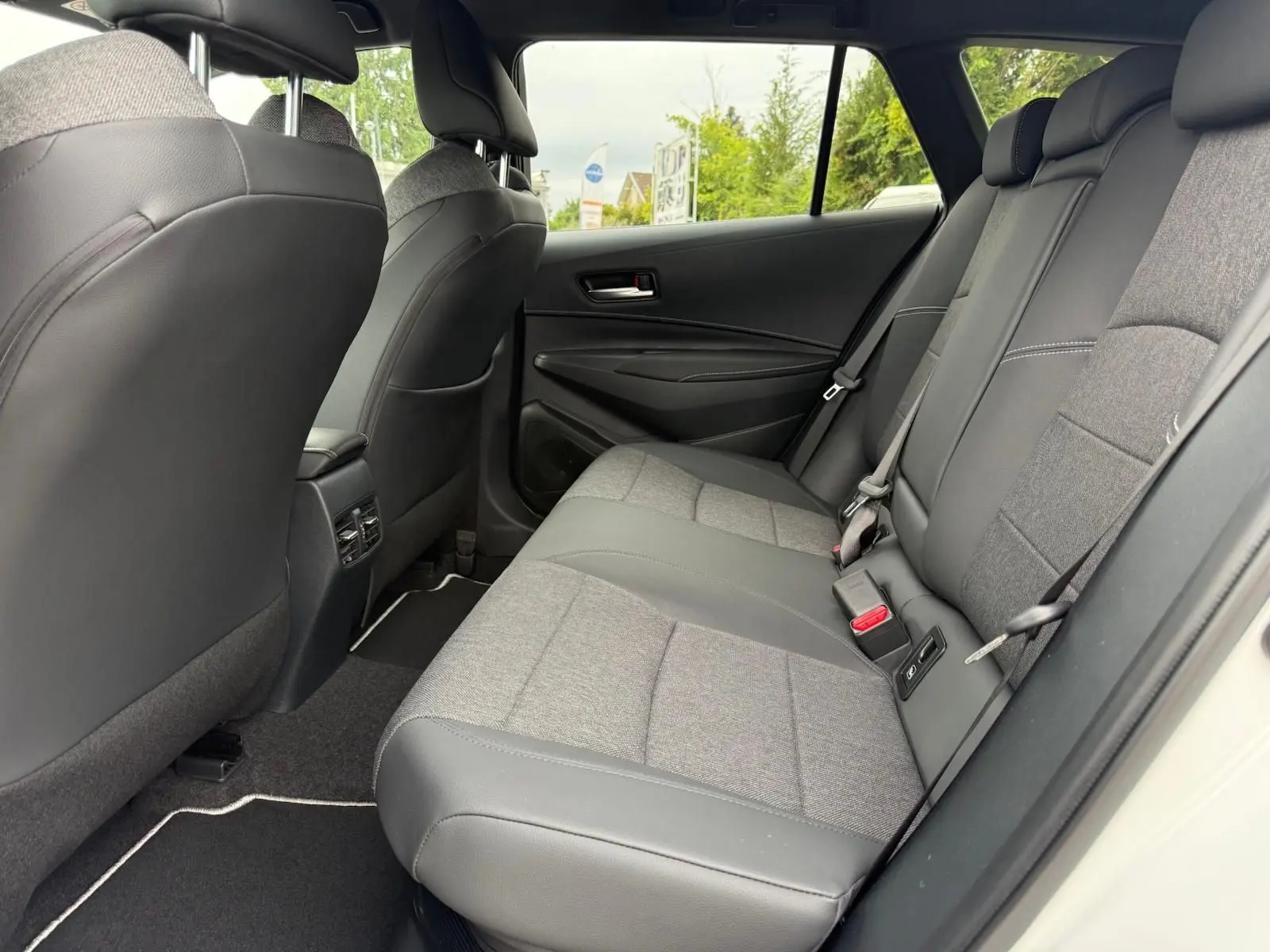 Vue côté droit de l'habitacle arrière de la Toyota Corolla Touring Sport 2025, sièges bi-matière gris et noir.