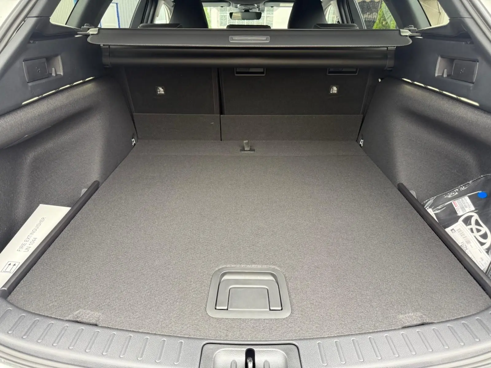 Coffre spacieux de la Toyota Corolla Touring Sport blanc lunaire nacré, vue arrière avec cache-bagages déployé.