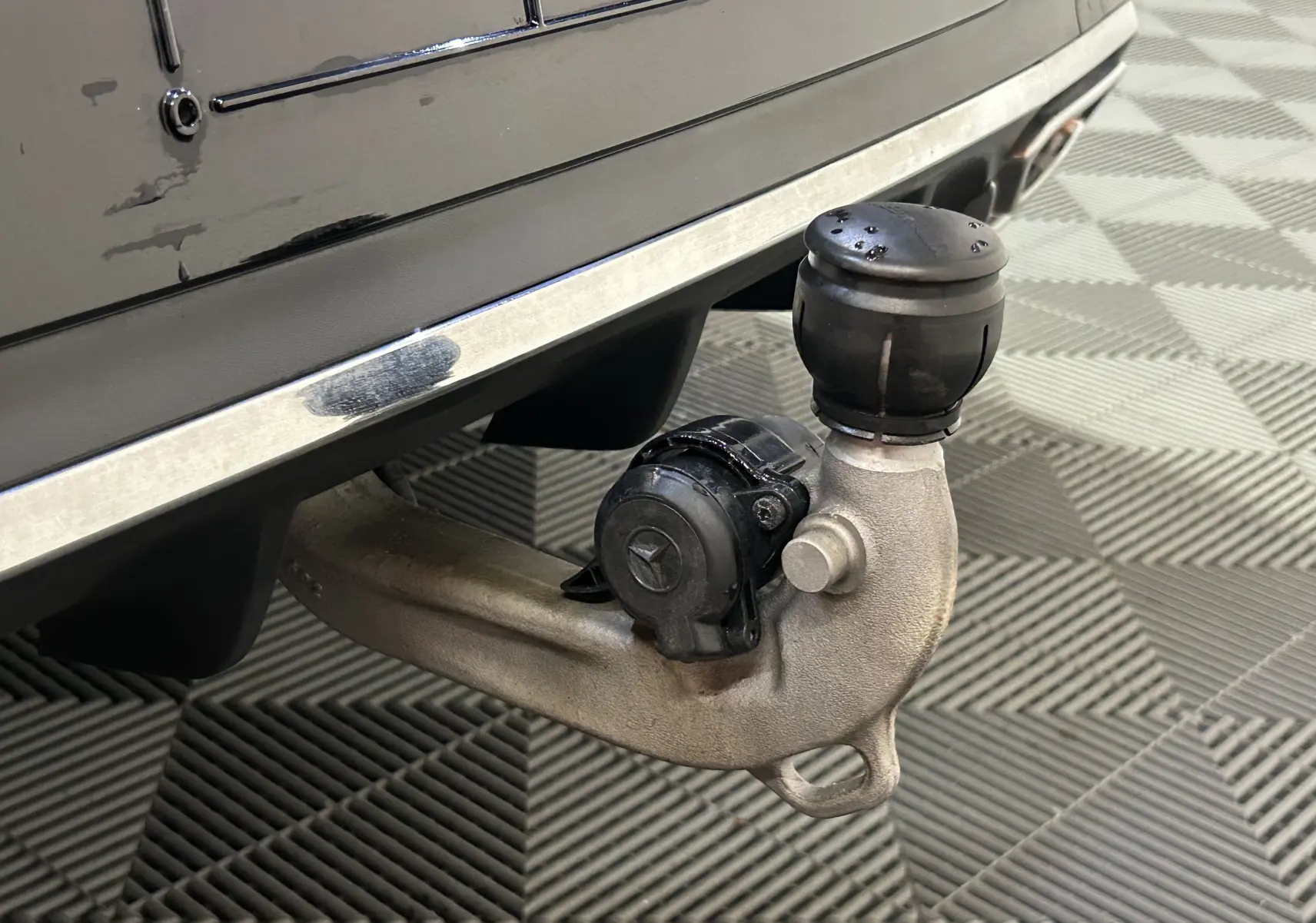 Gros plan sur l'attelage arrière droit noir métallisé d'une Mercedes Classe CLA Shooting Brake II 200D AMG.