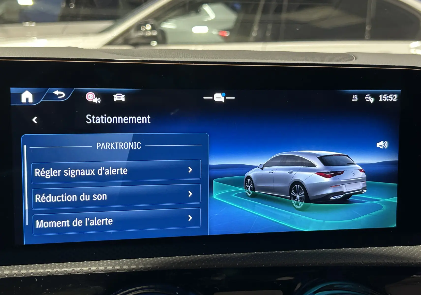 Écran multimédia montrant une voiture argentée vue en 3/4 arrière droite dans l'interface de stationnement Mercedes.