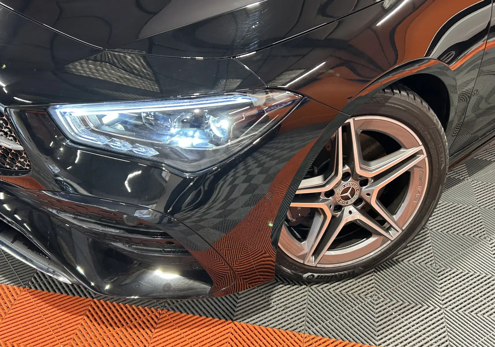 Gros plan sur l'avant droit noir métallisé d'une Mercedes Classe CLA Shooting Brake II 200D AMG avec jante AMG cinq branches.